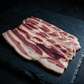 Raw pasture-raised chicken cut into eight pieces on dark slate